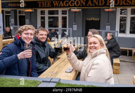 Brighton UK 12th April 2021 - Cheers these students  enjoy drinking outside the Waggon and Horses pub in Brighton as the next stage of lockdown easing begins in England with hospitality venues being allowed to serve outdoors : Credit Simon Dack / Alamy Live News Stock Photo
