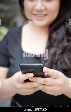 Close-up image of young woman using application on smartphone or texting friends Stock Photo