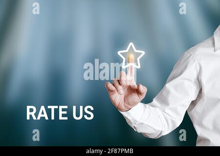Businessman pressing a star button with the word rate us on a virtual display screen. Customer rating and evaluation concept. Stock Photo