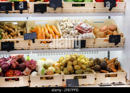 Variety of different vegetables сarrots, ginger, garlic, sweet potatoes, potatoes, onions, beets, tomatoes on shelves in supermarket. Vitamins and min Stock Photo
