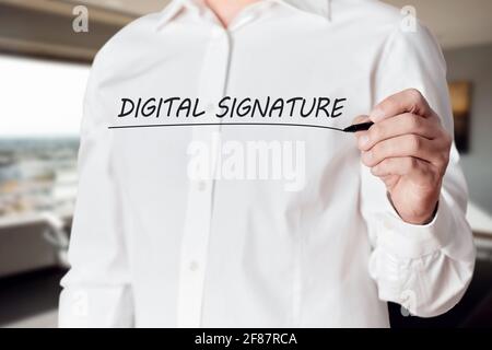 Businessman hand holds a pen and underlines the words digital signature on a virtual screen. Stock Photo