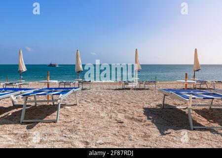 Empty beach loungers waiting for vacationers on a beautiful beach Stock Photo