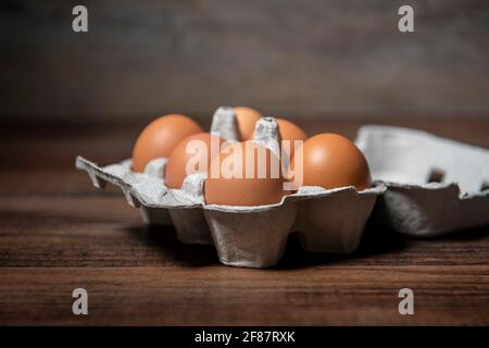 Fresh farm eggs in an eggbox on a wooden rustic table. Stock Photo
