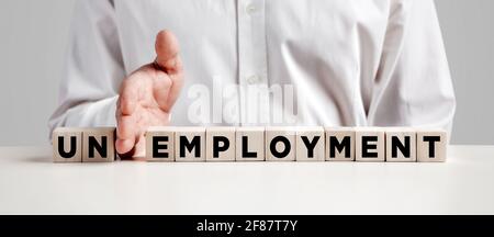 Businessman hand puts away the first two letters from the word unemployment and transforms it into employment. Solving unemployment problem. Stock Photo