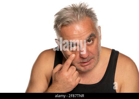 middle aged man pilling his lower eyelid on white background Stock Photo