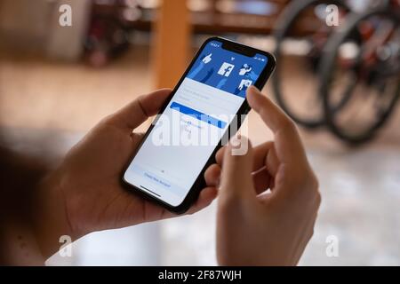 CHIANG MAI, THAILAND - FEB 26, 2020: Woman hold Apple iPhone XS with facebook application. Facebook is a social network and creating cryptocurrency Stock Photo