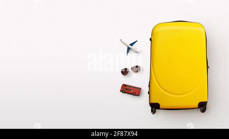 Plane, glasses and red bus next to yellow suitcase Stock Photo