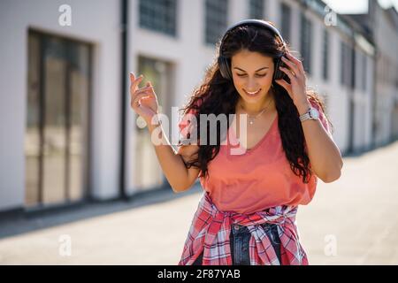 Happy young woman is enjoying sunny day outdoor in city. Stock Photo