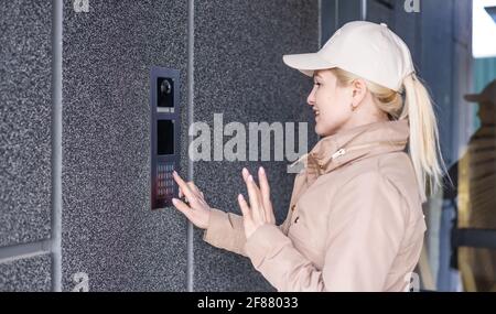 Close up the female hand presses the doorphone button. The girl is calling the intercom. Means of communication or notification of arrival and Stock Photo