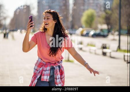 Happy young woman is enjoying sunny day outdoor in city. Stock Photo