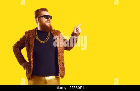 Happy man in funny leopard jacket and chain necklace pointing away to copy space Stock Photo