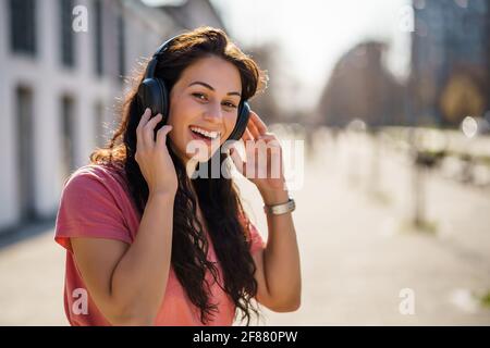 Happy young woman is enjoying sunny day outdoor in city. Stock Photo