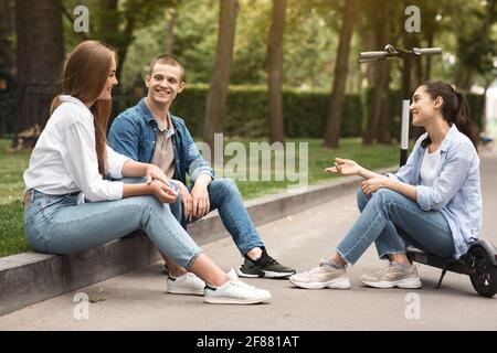 Three friends spending time in park and talking Stock Photo