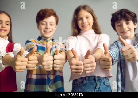 Studio group shot of happy little kids smiling and giving thumbs up all together Stock Photo