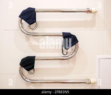 .Several cloth masks are dried on a radiator. Drying protective masks. Stock Photo