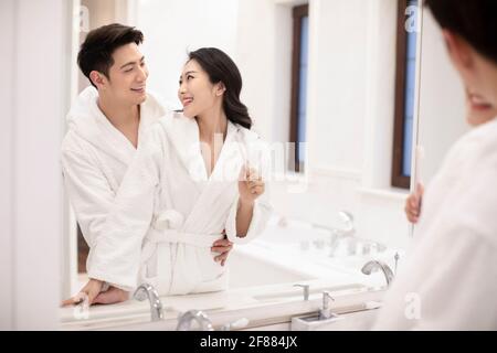 Happy young couple brushing teeth in bathroom Stock Photo