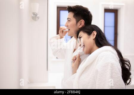 Happy young couple brushing teeth in bathroom Stock Photo