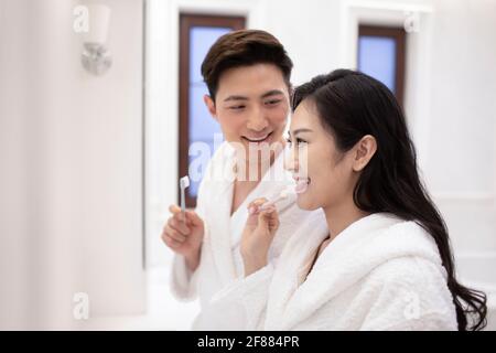 Happy young couple brushing teeth in bathroom Stock Photo
