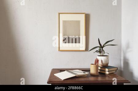 Wooden frames mockup. Flowerpot on a pile of books on an old wooden desk. Composition on a white wall background Stock Photo