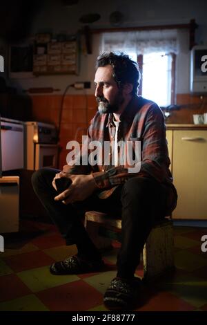 Portrait of poor mature man sitting indoors at home, poverty concept. Stock Photo