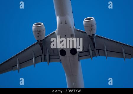 Helsinki / Finland - APRIL 11, 2021: Closeup of white airplane fuselage with two turbojet engines against bright blue sky. Stock Photo
