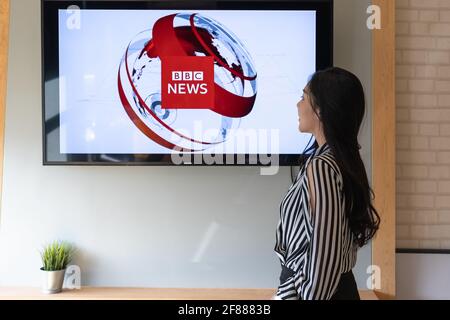 CHIANG MAI, THAILAND - JUN 05, 2020 : Woman watching BBC News on TV. BBC News reporting a breaking news item.