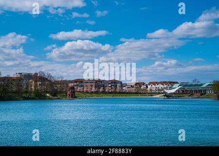 Freiburg im Breisgau, Germany, April 3, 2021, Blooming trees at waterside of seepark urban city park with some people enjoying springtime sun atmosphe Stock Photo