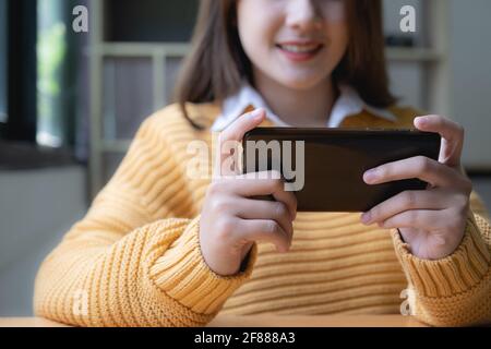 Young asian woman surprised by unbelievable good news, fantastic online travel offer looking at smartphone. Stock Photo