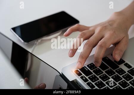 Man press turn off button laptop computer and turn off smartphone Social media disconnect and Technology ban social ban and digital detox concept. Stock Photo