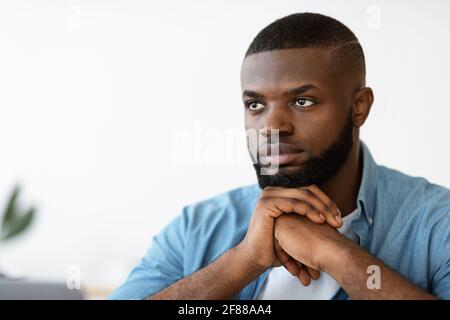 Closeup Portrait Of Serious Handsome Black Man Sitting With Pensive Face Expression Stock Photo