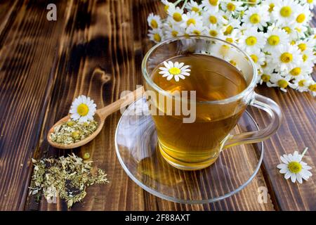 Tea in the glass cup with chamomile on the brown wooden background Stock Photo