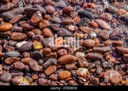 Colorful red beach stones in the waves along the North Shore of Lake Superior in Minnesota Stock Photo