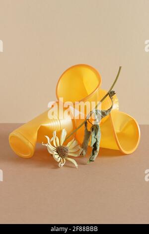 Crumpled empty plastic cups and dry flower on monochrome background, isometric view, plastic waste, waste recycling, eco friendly packaging, sustainab Stock Photo