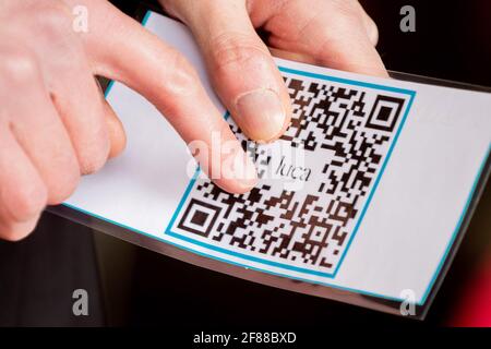 Berlin, Germany. 12th Apr, 2021. A security guard holds a check-in QR code from the Luca app at the entrance of a clothing store on Alexanderplatz. The app is used to provide data for possible contact tracing. Credit: Christoph Soeder/dpa/Ģ����ý Live News Stock Photo