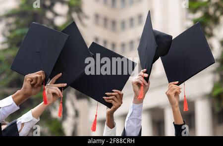 Cropped of students raising up hands with caps Stock Photo