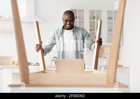 Excited african american man being happy of installing wooden desk by yourself after home relocation Stock Photo