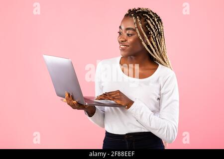 Smiling young black lady holding and using laptop Stock Photo