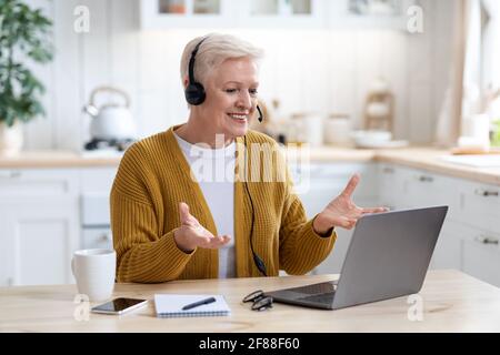 Happy old woman using laptop, having video conference Stock Photo