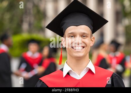 Handsome guy student posing in graduation costume Stock Photo