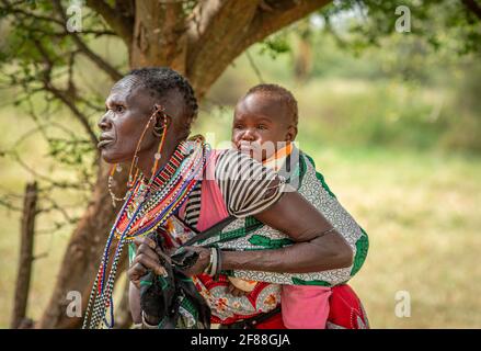 traditional African Maasai woman with baby wrapped to her back Stock Photo