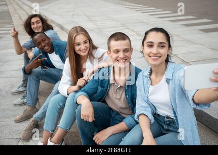 Five multiracial friends taking selfie using phone outdoors Stock Photo
