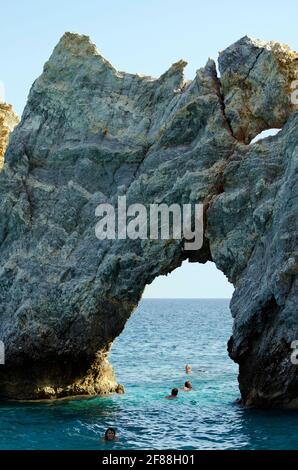 Skiathos, Greece - October 3rd 2012: unidentified people enjoy the clear sea, swimming through the rockhole on Lalaria beach - one of the landmarks of Stock Photo