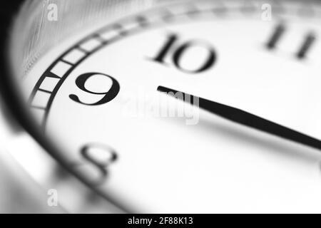 Clock hand pointing nine o'clock on white clock face of Twin bell classic alarm clock Stock Photo