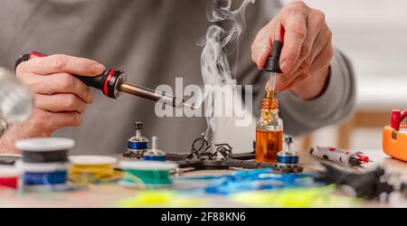 Closeup view of man hands during quadcopter repairing process using soldering iron and different tools Stock Photo