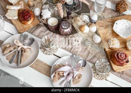 A festive table with beautiful dishes, decorative items and pastries. Easter table setting design idea. Stock Photo