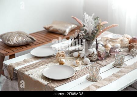 Empty plates and glasses on a decorated dining table for the Easter holiday. Beautiful hygge-style table setting. Stock Photo