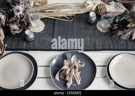 Stylish crockery and cutlery on a set table in coffee colors with Scandinavian-style decorative elements. Stock Photo