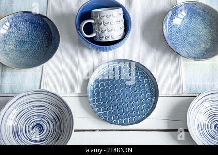 Empty ceramic tableware. Ceramic plates and cup on wooden surface. Overview empty food table with tableware. Set of different modern blue plates. Stock Photo