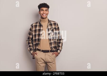 Photo of attractive cool dark skin young man hold hands pockets good mood isolated on grey color background Stock Photo