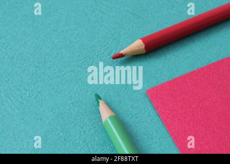 Back to school. Green and red pencils lie on colored background. Creative minimalistic concept of children's creativity, drawing. Stock Photo